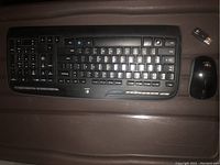 Logitech wireless keyboard and wireless mouse on brown surface with a USB receiver beside the mouse.