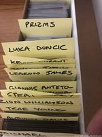Card box with dividers labeled PRIZMS, LUKA DONCIC, KEVIN DURANT, LEBRON JAMES, GIANNIS ANTETOKOUNMPO, ZION WILLIAMSON, TRAE YOUNG, ANTHONY DAVIS, MICHAEL JORDAN