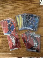 Photo of 11 NBA Mosaic Prizm basketball cards including 3 Genesis cards, 2 gold cards, and 6 red wave mosaic prizms, laid out on a wooden surface.