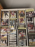 Front view of multiple white storage boxes with stacks of cards labeled Black Diamond, Gold Medallion, Young Guns