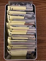 Top-down view of white storage tin filled with sleeved hockey cards separated by player notes