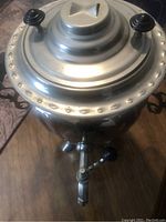 Top view of the samovar showing the lid with two black handles and the upper part of the spout.