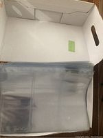 Top-down view inside a white shoebox showing stacks of transparent plastic card sleeves inside.