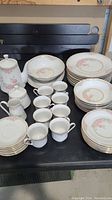 Full display of entire 44 piece china set including plates, cups, teapot, creamer, sugar bowl, and serving bowl arranged on a table.