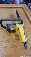 Yellow McCulloch chainsaw laying on a wooden surface showing side view with motor housing, handle and chain bar; used and worn condition visible.