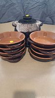 Front view showing two stacks of four brown ceramic bowls each placed beside the soup tureen.