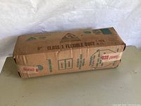 Photo showing the unopened cardboard box labeled with product information including 6 inch Class 1 Flexible Duct, 25 feet, Rubber Products, Inc. Fort Worth, Texas, UL listed.