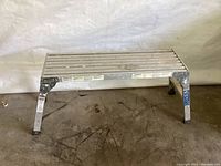 Full view of the aluminum work platform showing top standing surface and legs.