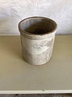 Side view of the 3 gallon stoneware crock showing stamped design and surface discoloration.