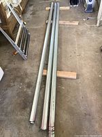 Stack of galvanized steel Z bars approximately 10 feet long laid side by side on wooden blocks on garage floor