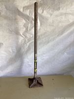 Full view of garden tamper showing wooden handle and metal tamping base