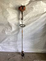 Full view of the Husqvarna gas grass trimmer showing the shaft, handle, and trimming head with cutting blade.