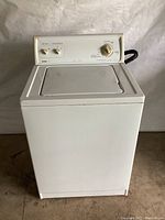 Front view of white Kenmore washing machine with lid closed and control panel with knobs visible.