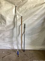 Three paint poles of different lengths and materials against a white backdrop.
