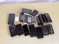 Top view of the collection of smartphones and an iPod laid out on a surface, showing screen conditions including multiple cracked screens