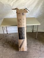 Full view of the Blue Hawk carpet tack strips box standing upright on floor in front of a table