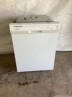 Closed front view of the white Whirlpool dishwasher showing the control panel on the top edge.