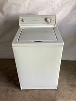 Front view of the white Whirlpool top-load washing machine showing lid and overall condition.