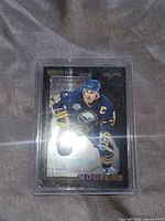Front image of Alexander Mogilny Black Ice hockey card featuring player skating in Buffalo Sabres uniform.