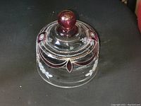 Front view of cranberry glass butter dish lid showing cranberry knob, delicate gold overlay, and white floral hand-painted designs.