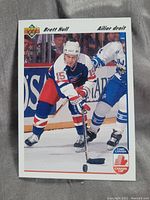 Front image of hockey card displaying Brett Hull in a blue, white, and red hockey uniform in action during a game, with Canada Cup logo visible.