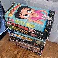 Photo of the lot of seven older VHS tapes stacked with visible spine labels and artwork including Betty Boop, Pulp Fiction, Fight Club, Soccer Dog, The Sixth Sense, and The Others.