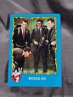 Front of Ghostbusters II movie card showing characters with proton packs in the 'Boxed In' scene framed by blue and yellow design.