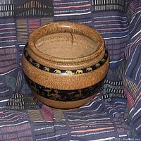 Round wood turned flower pot with natural wood finish and decorative black bands featuring gold elephant and human tribal figures.
