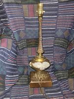 Full view of the lamp showing the tall brass stem, glass base with floral paint, and wooden platform.