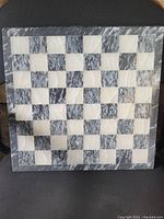 Front view of the marble and onyx chess board showing alternating dark grey marble and light onyx squares in a 14x14 layout.