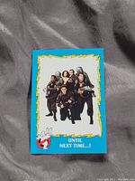 Photo of Ghostbusters trading card featuring the main cast in proton packs with the message 'Until Next Time...!' and Ghostbusters logo.