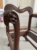 Close-up of one armrest showing detailed carved ram's head design with curling horns.