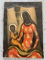 Front view of antique primitive icon painting depicting a seated woman with halo holding a child also with halo, both in patterned garments.