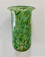 Full view of the green and yellow mottled art glass vase with a flared rim and cylindrical body.