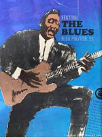 Image of the front section of the vintage blues concert poster showing an illustration of a blues guitarist in a black suit playing an electric guitar with blue background.