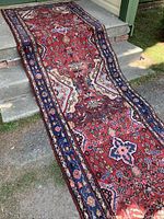 Full-length view of red Persian wool runner draped over stone steps outdoors