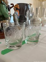 Two of the tumblers showing clear glass with etched cornflower floral design featuring frosted petals and geometric center.