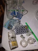 Various crystal and glass dining and decorative items on table including pitchers, cream and sugar set, candy dishes, napkin rings and others.