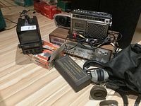 Wide view showing all items including Realistic CB radio in black case with handset, Sony cassette/radio with cables, Sears amplifier under Sony unit, Candle TV/radio, older headphones, small radio, TV antenna, and cables.
