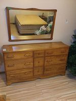 Full view of the dresser with mirror mounted on wall above it, showing overall condition and style.