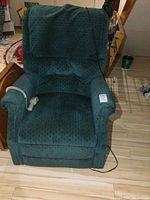 Front view of green fabric power reclining lift chair with attached remote control placed on left armrest, minor wear visible on fabric.