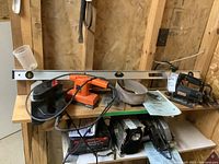 Photo showing Craftsman scroll saw on wooden workbench alongside Black & Decker orange sander polisher, Craftsman dustless belt sander, two hand planers, and a level on top of the tools.
