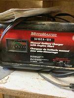 Photo of MotoMaster 50/10/2 A - 12 V manual battery charger with label and power cord visible