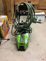 Front view of the Greenworks pressure washer with hose wrapped around handles, showing overall device.