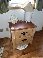 Photo of wood two drawer side table with various items displayed on and under it
