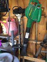 Green Weed Eater electric leaf blower and Stihl FS 52 gas weed trimmer side by side, showing overall condition and presence of wear