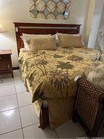 Full view of the made bed with wood headboard, bedding comforter, and pillows
