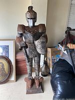 Full view of the rusted brass knight armor statue standing upright with shield