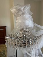 Full view of the chandelier partially wrapped in bubble wrap showing the silver toned frame and hanging crystals.