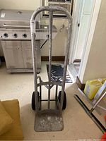 Front view of metal hand truck dolly showing frame, handle, and deflated tires.